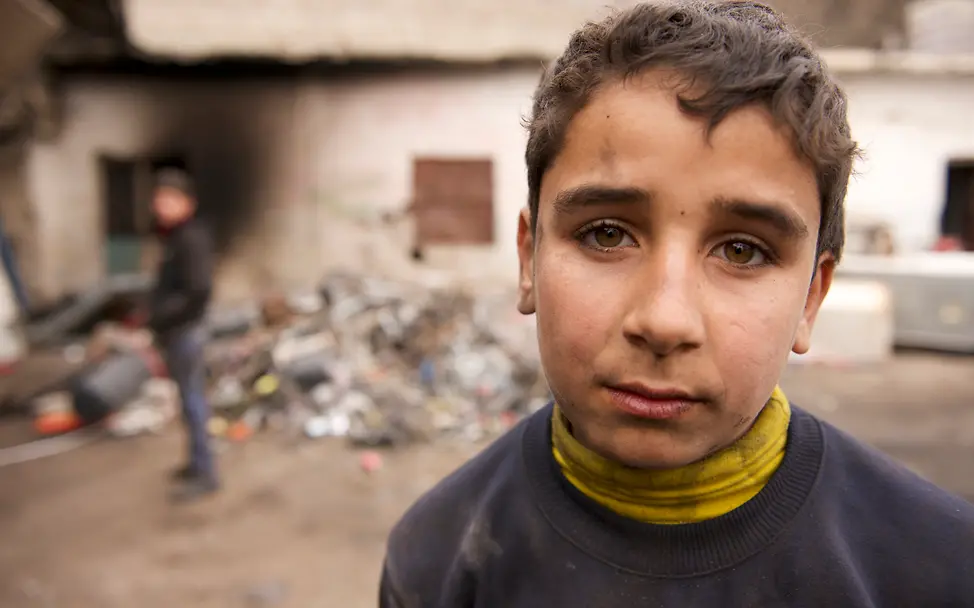 Ahmed arbeitet in einer Recycling-Anlage | © UNICEF/Noorani Der 14-jährige Ahmed steht vor der Recycling-Anlage. Sein Blick zeigt wie anstrengend die Arbeit für ihn ist.