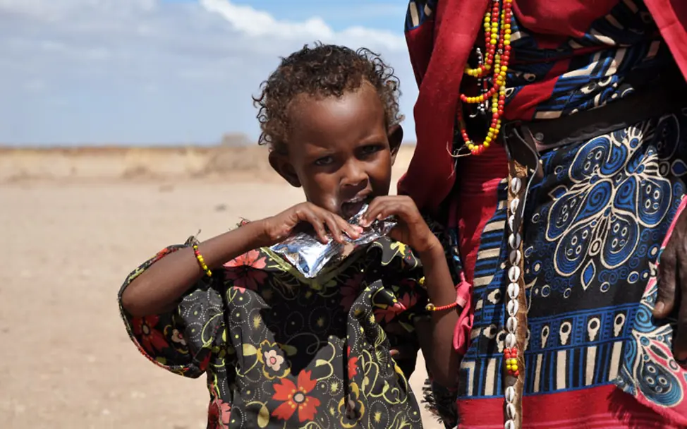 Medina isst die Ernusspaste aus der mobile Klinik | © UNICEF/Ninja Charbonneau Kenia: Medina isst ein Päckchen Ernusspaste