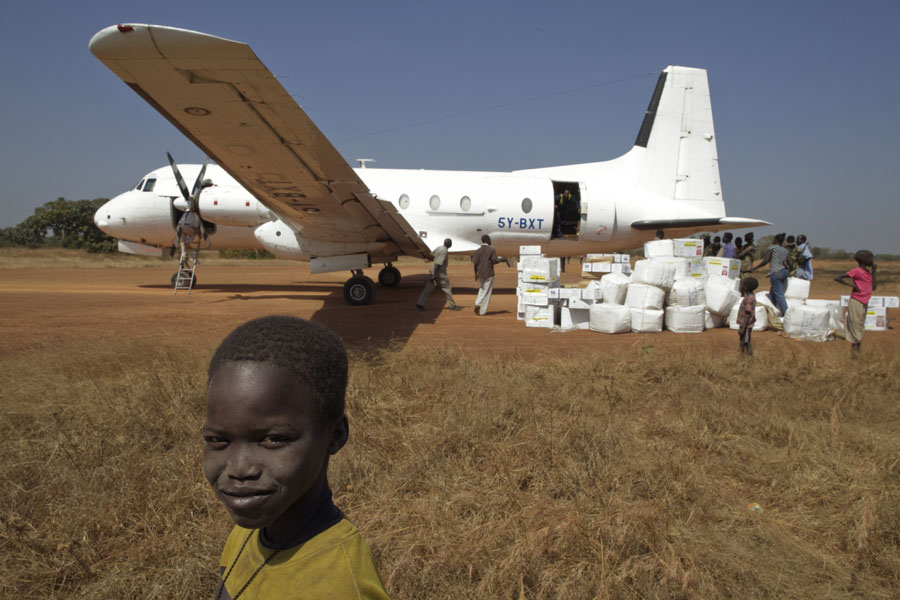 Ein Kind beobachtet wie ein Flugzeug entladen wird | © UNICEF/Sokol Südsudan: Ein Flugzeug mit Hilfsgütern wird entladen