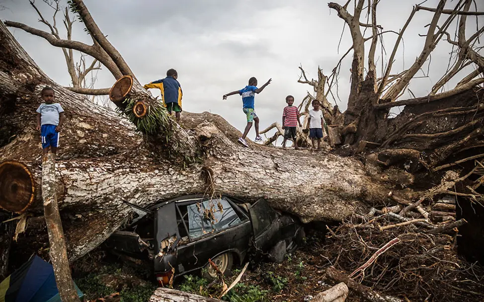 Naturkatastrophen sind eine Folge des Klimawandels. | © UNICEF/Sokhin klimawandel folgen kinder: Vier Kinder spielen auf einem umgestürzten Baum.