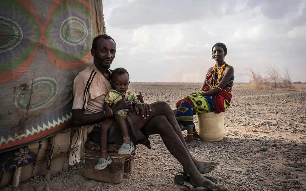 Ali und seine Familie leiden unter der Dürre in Kenia. | © UNICEF/Knowles-Coursin kilmawandel folgen kinder: Ali sitzt mit seiner Tochter und seiner Frau vor ihrem Zelt.