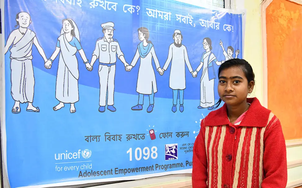 Maina holte sich Unterstützung von UNICEF. | © UNICEF/Boro Indien: Die 16-jährige Maina steht vor einem UNICEF-Plakat.