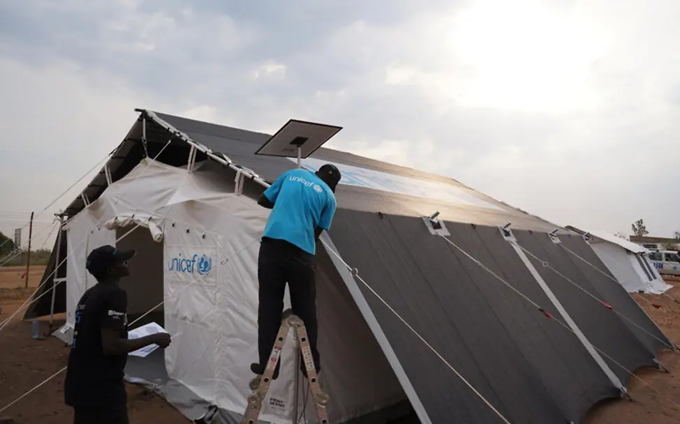 Uganda: Die Solaranlage des neuen Zeltes wird installiert | © UNICEF/Kakooza Hilfsgüter in Uganda: Die Solaranlage des neuen Zeltes wird installiert.