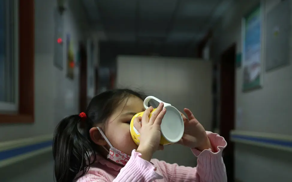 Wo alles begann: Wuhan/China 2020. | © UNICEF/Cui Wuhan: Ein Mädchen trinkt aus einer Tasse im Flur eines Krankenhauses.