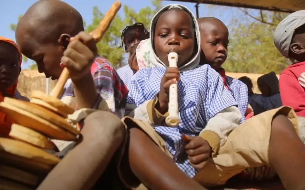 Ein Junge spielt mit einer weißen Blockflöte. | © UNICEF/Rai Kinder und Musik: Ein Junge spielt auf einer Blockflöte.