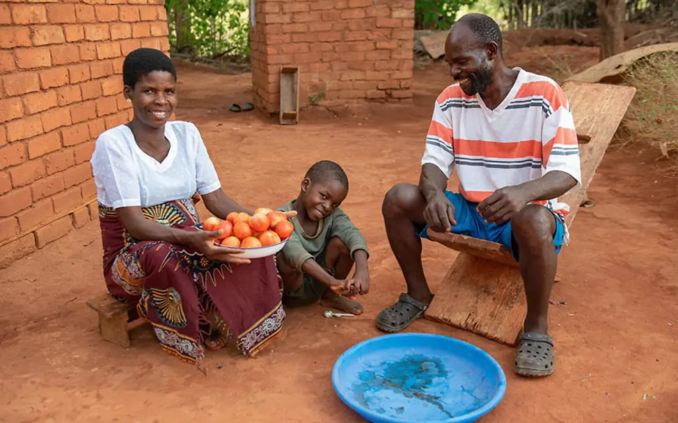 Durch den eigenen Anbau gesunder Lebensmittel sparen Familien Geld. | © UNICEF Malawi: Eine Familie zeigt ihre frisch geernteten Tomaten aus eigenem Anbau.