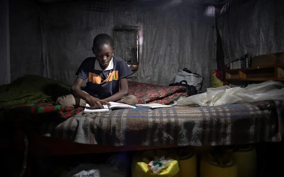 Kenia: Rafael kann ohne Mobiltelefon am Online-Unterricht nicht teilnehmen. | © UNICEF/Everett Kenia: Junge sitzt über einem Schulbuch, da er nicht am Online-Unterricht teilnehmen kann.