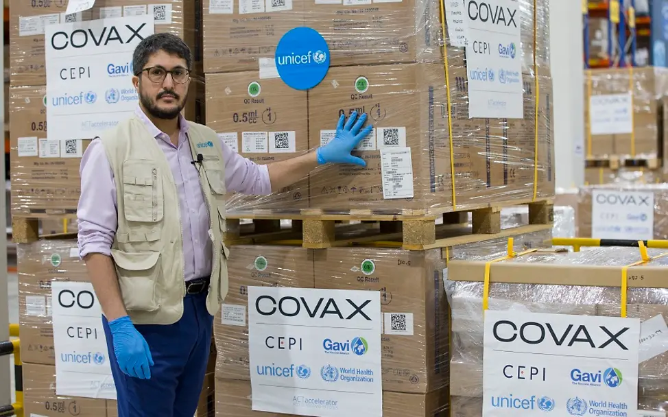 COVAX: Spritzen lagern im Warenlager in Dubai | © UNICEF/Pableo COVAX: UNICEF-Mitarbeiter steht in Dubai vor Palletten mit Spritzen für die Corona-Impfungen.