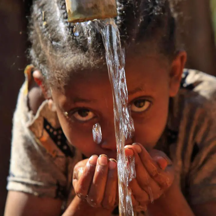 Wasser für Kinder in Äthiopien: UNICEF baut Brunnen und sorgt für sauberes Trinkwasser | © UNICEF/NahomT Wassermangel in Äthiopien: Ein Mädchen trinkt an einer Wasserstelle frisches Wasser aus ihren Händen.