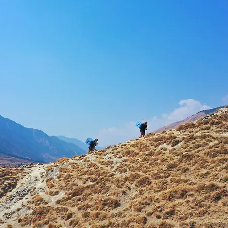 In der Ferne sieht man neben Gebirgsketten zwei UNICEF-Helfer, die den Corona-Impfstoff transportieren. | © UNICEF/UN0431111 In der Ferne sieht man neben Gebirgsketten zwei UNICEF-Helfer, die den Corona-Impfstoff transportieren.