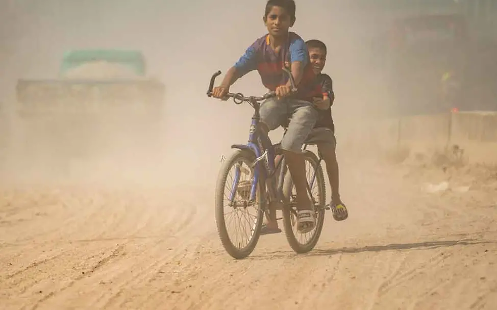 Kinder spielen auf einem Fahrrad auf einer stark verschmutzten Straße in Bangladesch I © UNICEF/Haque Lungenentzündung verursacht durch Luftverschmutzung in Bangladesch