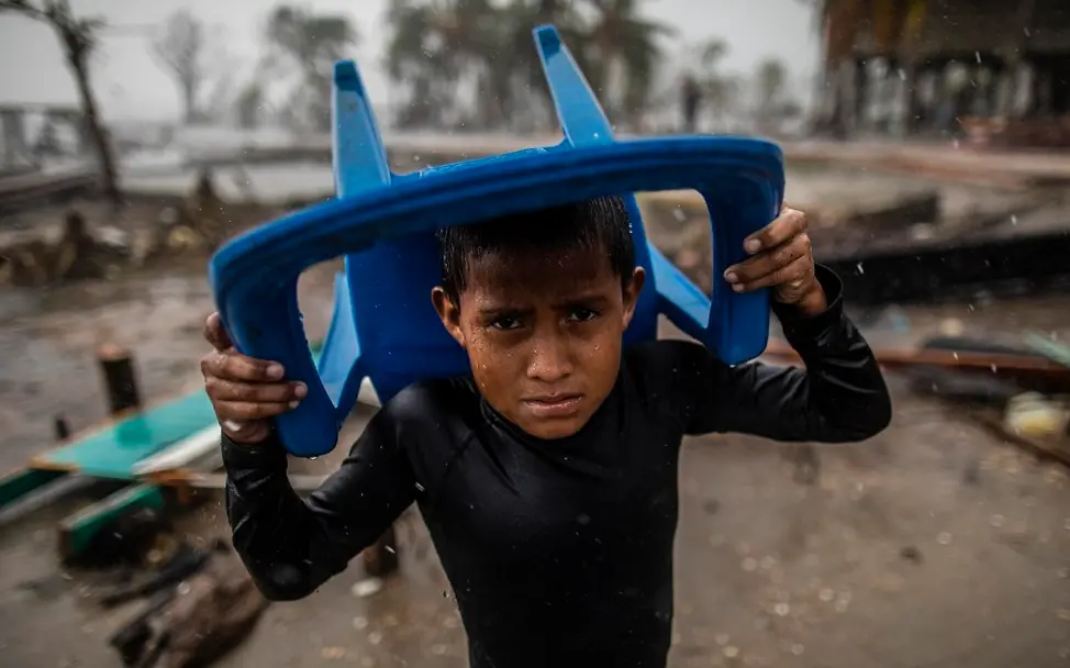 Nicaragua: Klimawandel | © UNICEF/Ocon/AFP-Services Klimaschutz spenden: Ein Junge in Nicaragua schützt sich mit einem Plastikstuhl vor Starkregen