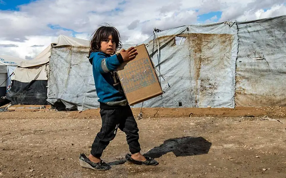 Syrische Kinder leiden unter Gewalt und Flucht und im Winter zusätzlich unter Kälte | © UNICEF/Souleiman Spenden für Syrien: Ein Mädchen in einem Flüchtlingslager trägt eine Kiste mit UNICEF-Kleidung.