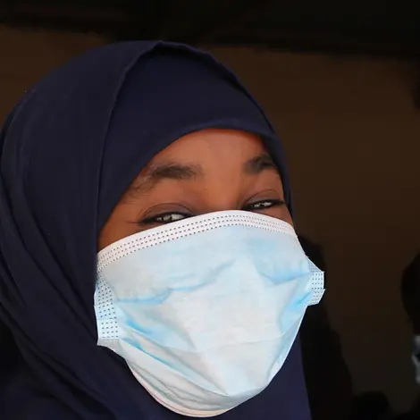 Anzal spielt mit der Kamera und grinst breit unter ihrer Maske. | © UNICEF/Kesper Anzal grinst in die Kamera.