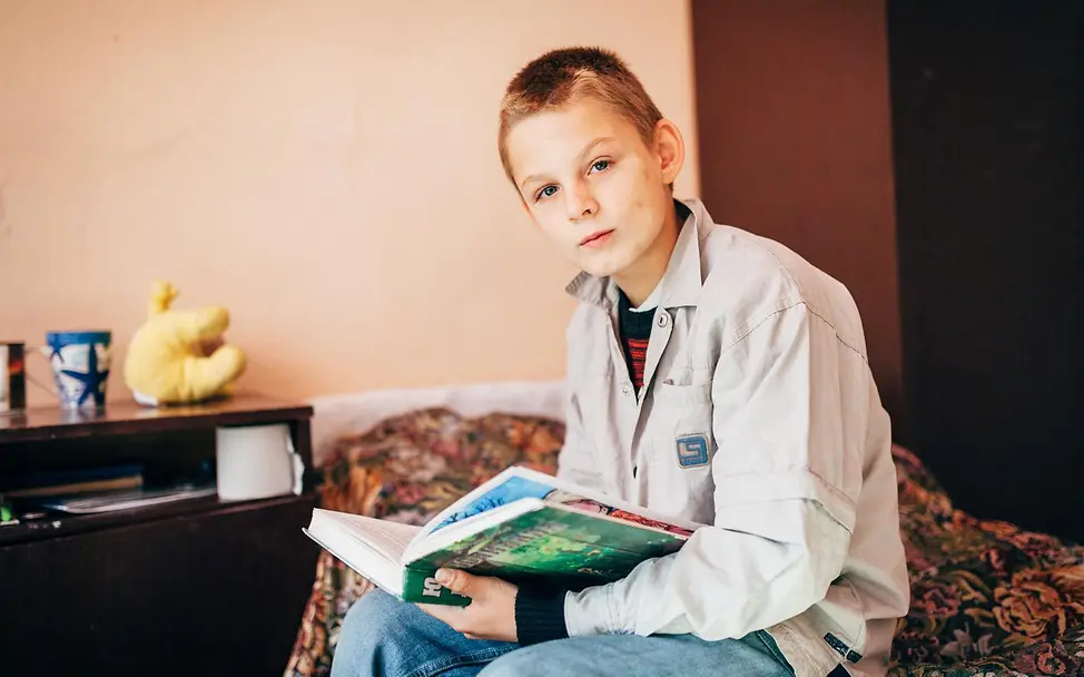 Ukraine: Vova sitzt auf dem Bett der Notunterkunft. | © UNICEF/Krepkih Ukraine: Vova wurde aus seiner Heimatstadt Brjanka in der Region Luhansk aufgrund des anhaltenden Konflikts vertrieben.