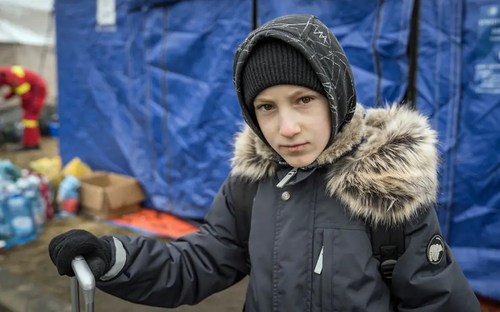 Geflüchtet: Ein ukrainischer Junge hat in seinem Rollkoffer ein paar Habseligkeiten mitgenommen. | © UNICEF/Moldovan Ukraine Flüchtlinge Kinder: Yaroslav hält den Griff seines Rollkoffers fest. Er konnte nur wenige Sachen mitnehmen.