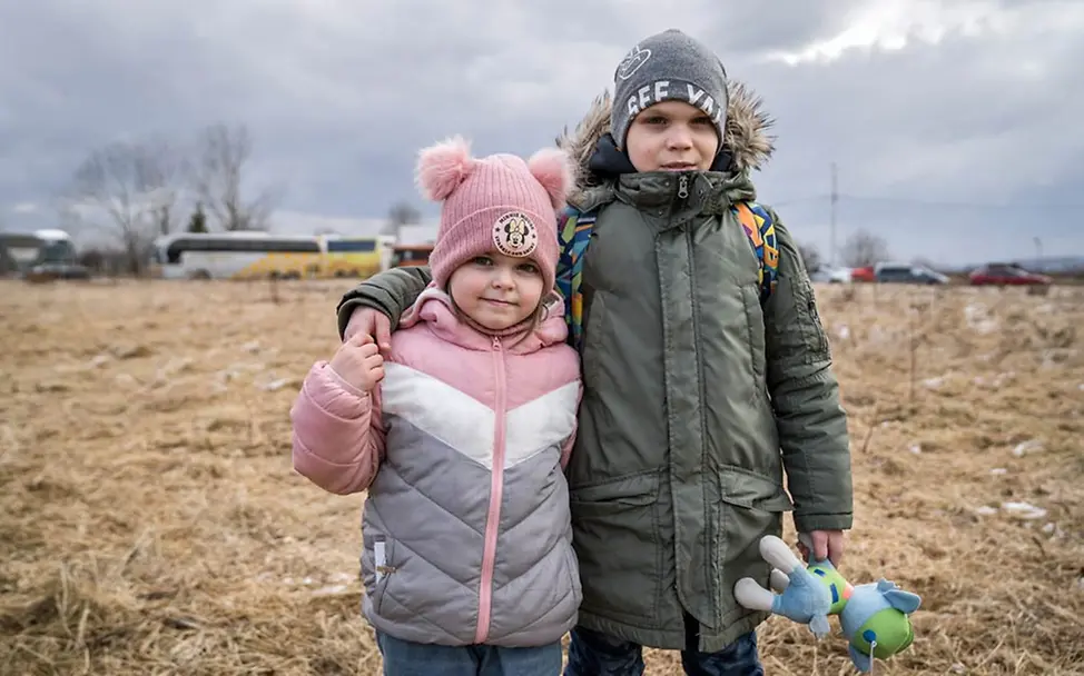 Die Geschwister Divia und Damia aus der Ukraine stehen Arm in Arm auf einem Feld. | © UNICEF/Moldovan Ukraine Flüchtlinge Kinder: Geflüchtete Kinder und Jugendliche brauchen Schutz und Unterstützung, um in Sicherheit zu leben.