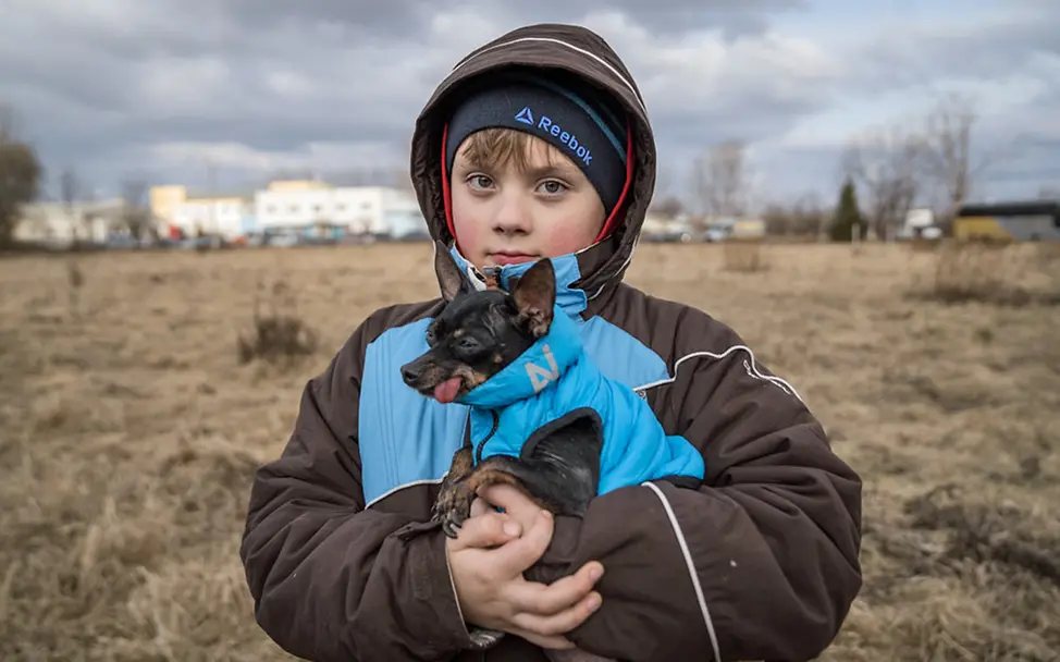 Ein ukrainischer Junge hat seinen kleinen Hund bei der Flucht mitgenommen. | © UNICEF/Moldovan Ukraine Flüchtlinge Kinder: Alexander hält seinen kleinen Hund schützend im Arm.