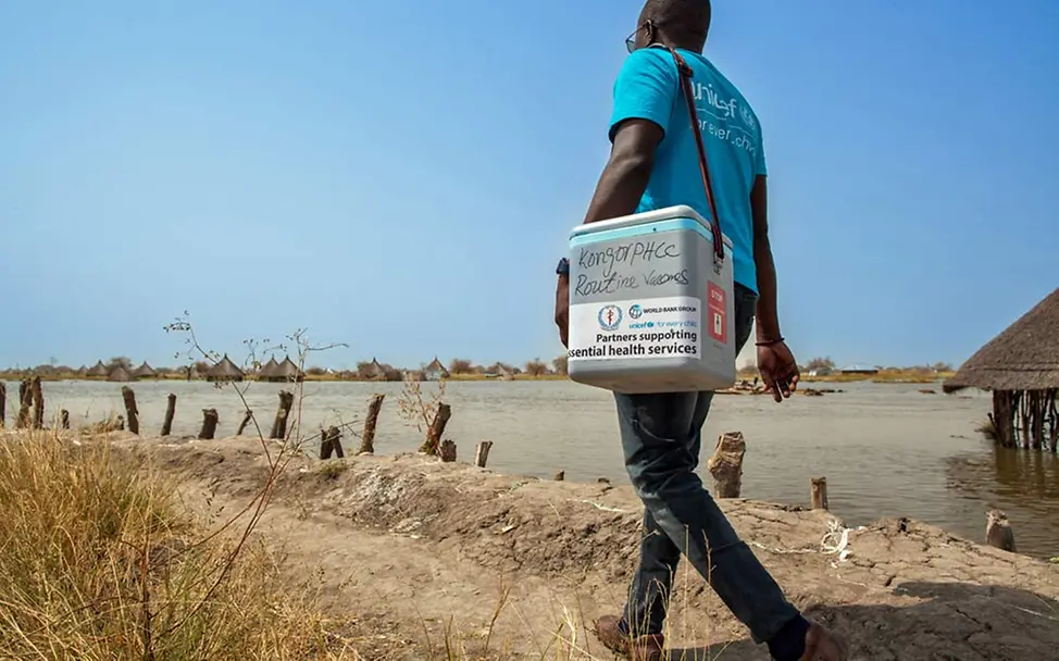 Südsudan: Ein UNICEF-Helfer bringt eine Kühlbox mit Impfstoffen. | © UNICEF/Naftalin Impfungen für entlegene Regionen: Ein Helfer bringt eine Kühlbox mit Impfstoffen.