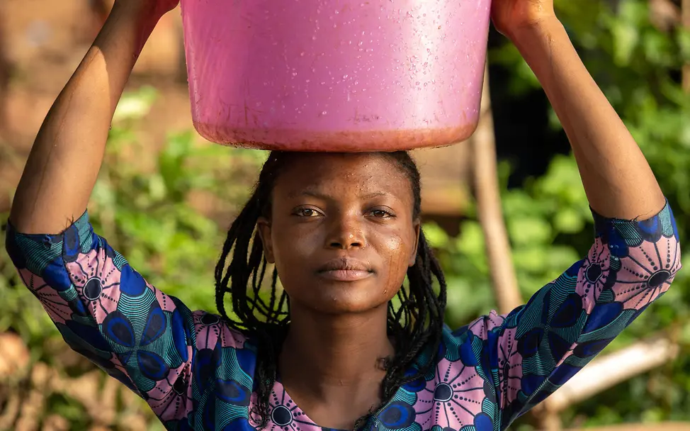 Wasser aus einer sicheren Quelle. | © UNICEF/Dubourthoumieu Im Kampf gegen Cholera schöpft Souza Mbomba (19) Wasser aus einer von UNICEF erschlossenen Wasserquelle.