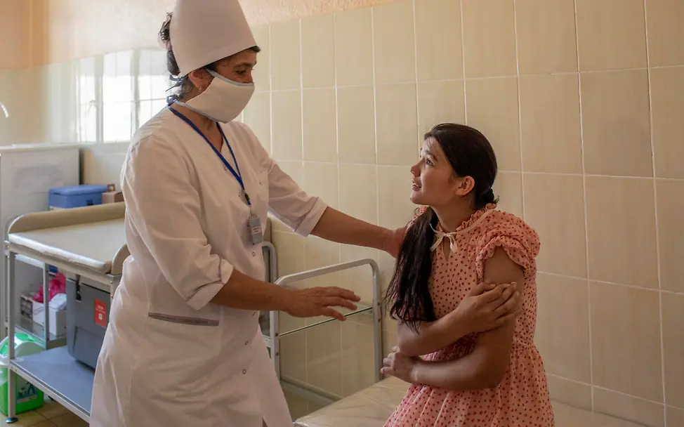Sich Zeit nehmen, gut erklären und Zuhören sind Shakhrizoda wichtig. © UNICEF/Babajanyan VII Photo Shakhrizoda hört ihrer Krankenschwester Djuraeva genau zu, bevor sie die erste Dosis des HPV-Impfstoffs erhält.