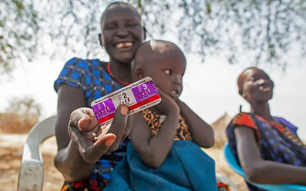 Malaria-Medikamente helfen bei der Bekämpfung der Infektionskrankheit. | © UNICEF/Naftalin Eine lächelnde Mutter im Südsudan zeigt das Malaria-Medikament für ihre infizierte Tochter.