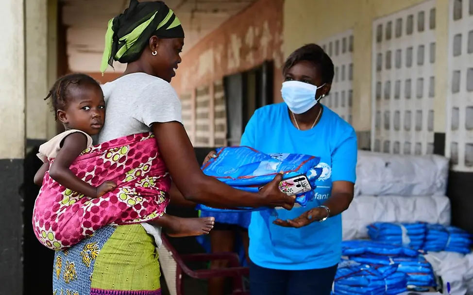 Malaria: UNICEF verteilt Millionen Moskitonetze als Malaria-Prophylaxe zum Schutz vor den Stechmücken. | © UNICEF/Dejongh Eine UNICEF-Mitarbeiterin gibt einer Mutter Moskitonetze für ihre Familie.