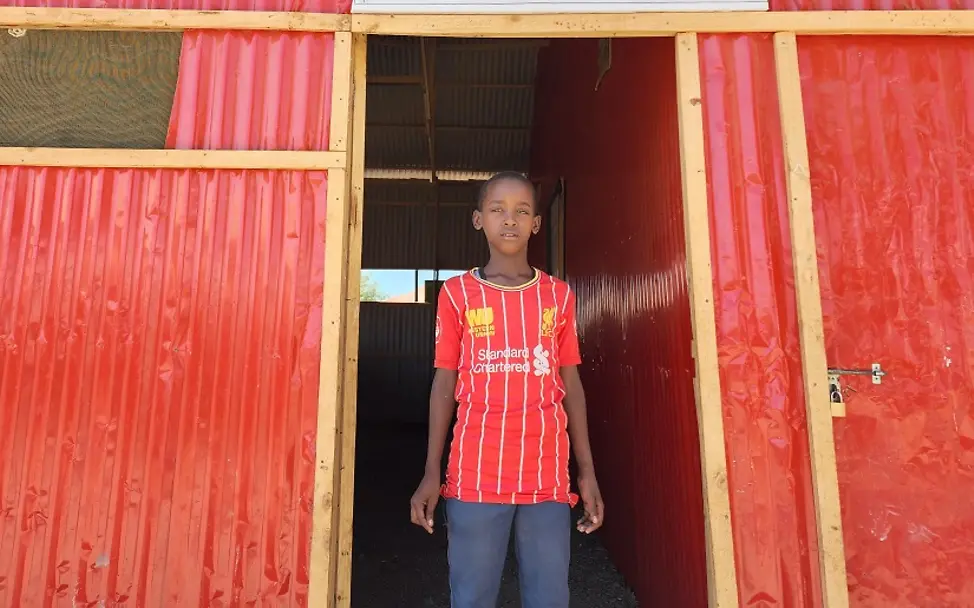 Adan musste wegen der Dürre fliehen I UNICEF Somalia/Mumin Adan steht vor dem Eingang eines Gebäudes im Binnenvertriebenenlager.
