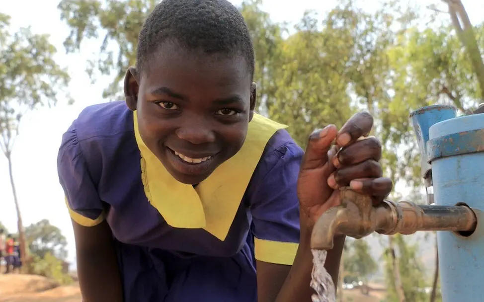 Eine Schülerin steht neben einem Wasserhahn, aus dem Trinkwasser fließt | © UNICEF/Chagara Living Schools Malawi: Eine Schülerin steht an einem Wasserhahn, aus dem sauberes Trinkwasser fließt