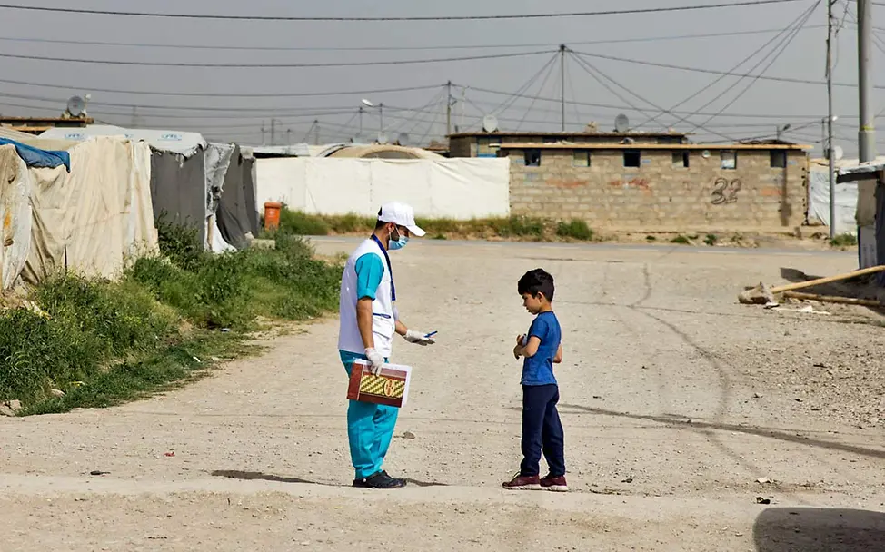 Ein UNICEF-Mitarbeiter und ein geflüchteter Junge in einem irakischen Flüchtlingscamp | © UNICEF/Njiokiktjien Irak humanitäre Hilfe: Ein UNICEF-Mitarbeiter spricht in einem Flüchtlingscamp mit einem Jungen.