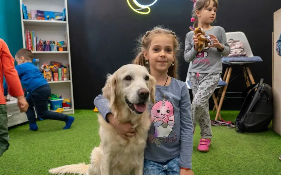 Ukraine: Hunde-Therapie in einem UNICEF Spilno © UNICEF/Filippov Kinder im Ukraine-Krieg: Ein Mädchen sitzt mit Therapiehund in einem UNICEF-Kinderzentrum.