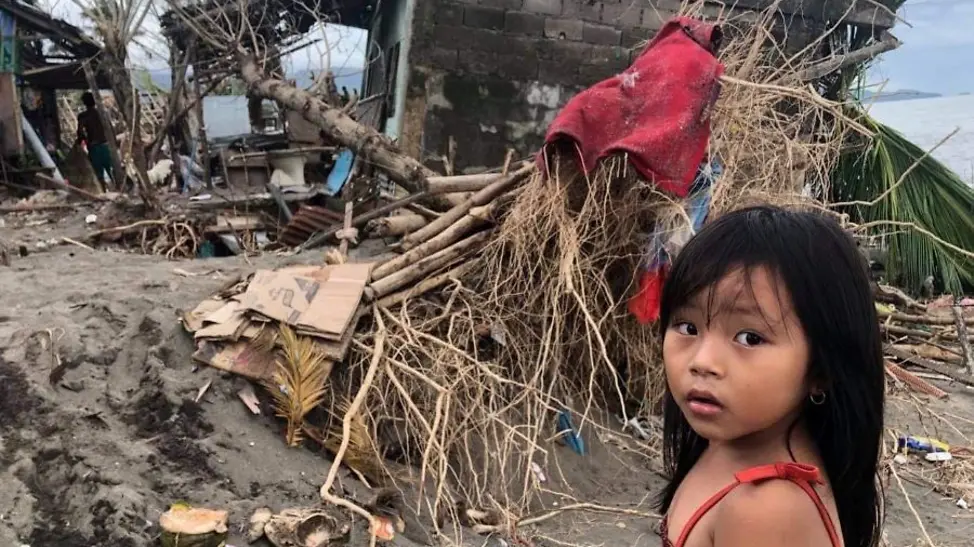 Philippinen: Zerstörung durch Taifun | © UNICEF/Saldico Mädchen steht vor durch Taifun zerstörte Häuser.