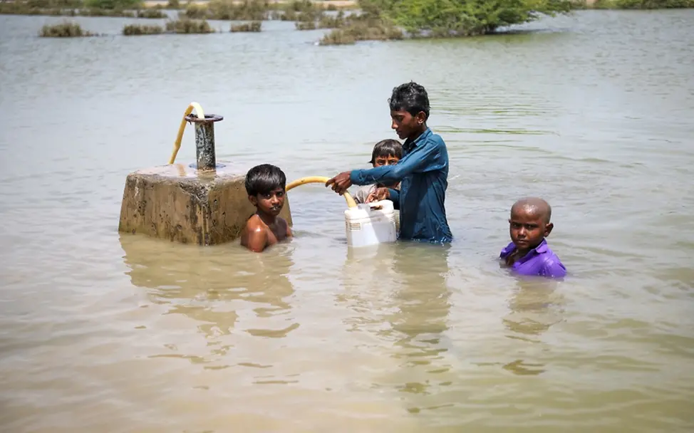 Kinder versuchen Trinkwasser aus einer überfluteten Wasserpumpe zu retten. | © UNICEF/UN0701707/Zaidi Kinder versuchen Trinkwasser aus einer überfluteten Wasserpumpe zu retten.
