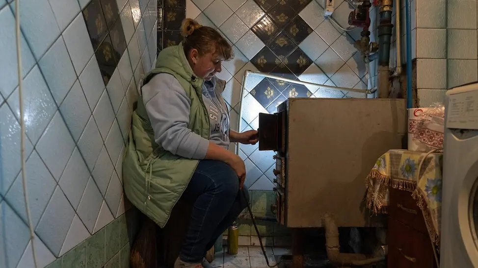 Ukraine Winter Nothilfe: Eine Frau feuert einen Heizkessel an mit Briketts, die sie von UNICEF bekommen hat 