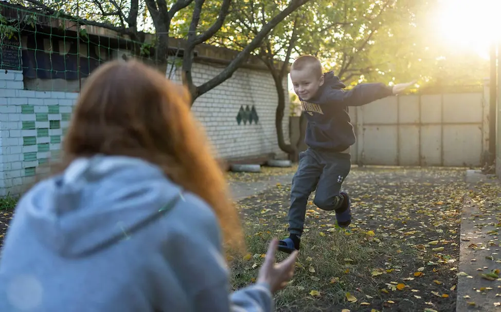 Ukraine Winter Hilfe: Zwei geflüchtete Geschwister spielen im Hof ihres Hauses