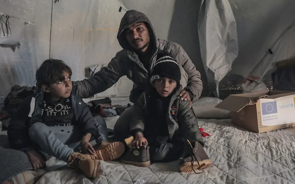 In Gaza verschärfen kalte Temperaturen die Not der Menschen. | UNICEF/Nateel Gaza: Kinder sitzen mit warmen Jacken in einem Zelt
