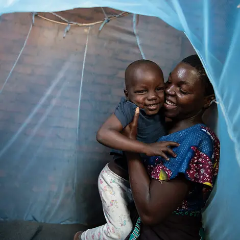 Malaria Kinder schützen: UNICEF hilft Millionen Kindern im Kampf gegen die Malaria-Erkrankung | © UNICEF/Chikondi Schutz vor Malaria: Eine Mutter in Malawi hält ihren Sohn unter einem Moskitonetz im Arm.
