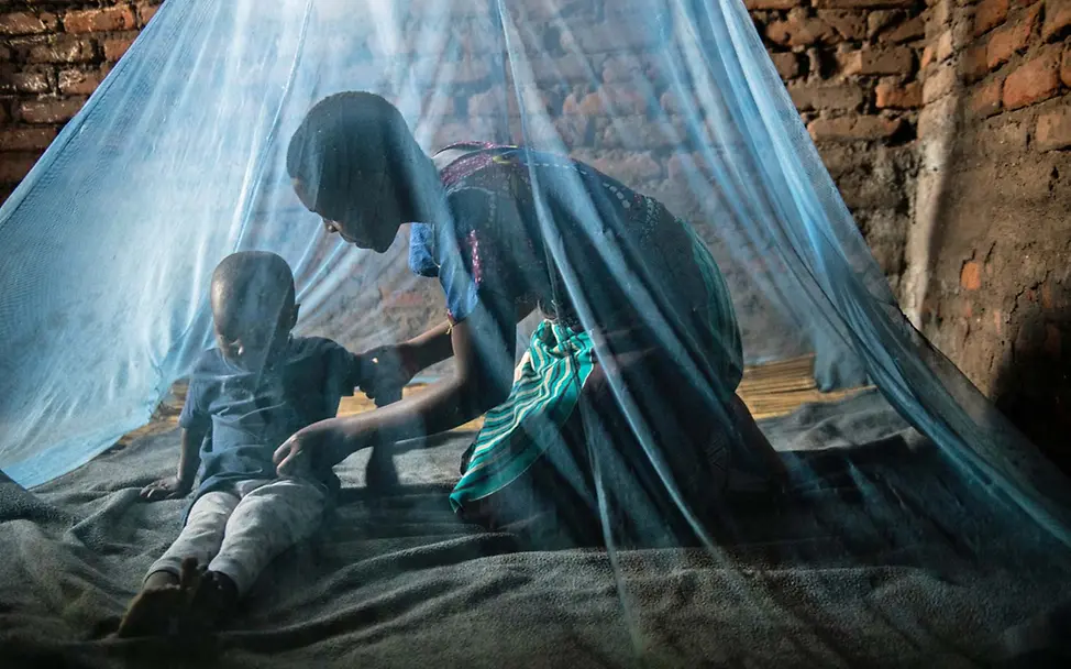 Unter dem Moskitonetz sind diese Mutter und ihr Sohn gegen den Stich der Mücken geschützt | © UNICEF/Chikondi Malaria Kinder schützen: Eine Mutter mit ihrem Sohn unter einem Moskitonetz