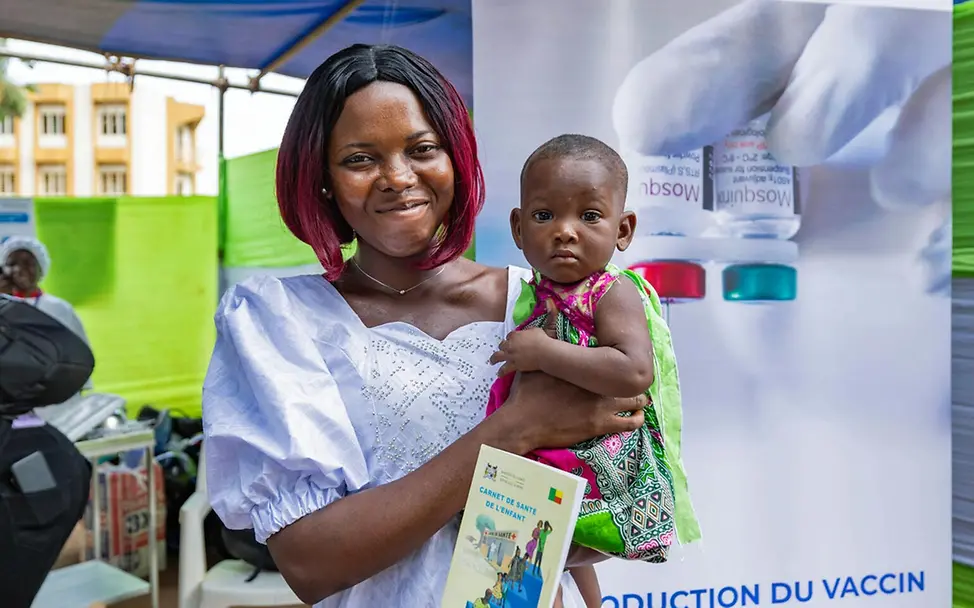 Eine Mutter in Benin hat ihre Tochter gegen Malaria impfen lassen | © UNICEF/Koklannou Malaria Kinder schützen: Eine lächelnde Mutter mit ihrem Baby auf dem Arm, das eben gegen Malaria geimpft wurde.