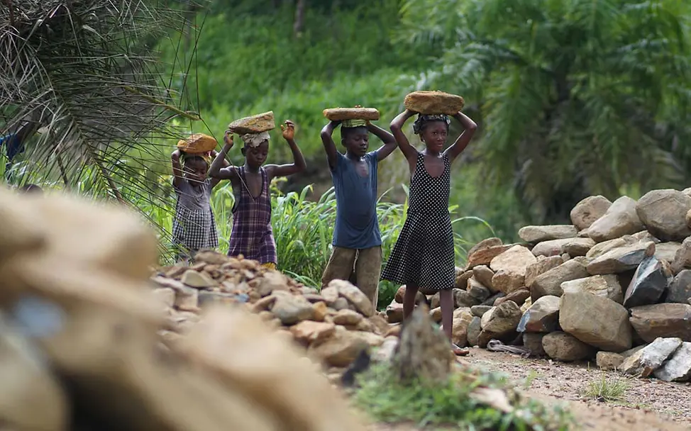 Was kann man gegen Kinderarbeit tun: Arbeitende Kinder in einem Steinbruch in Sierra Leone tragen Steine auf ihren Köpfen. 