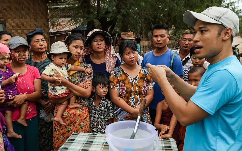 Erdbeben Myanmar spenden: Ein UNICEF-Helfer erklärt Menschen die Nutzung von Wasserreinigungstabletten. 