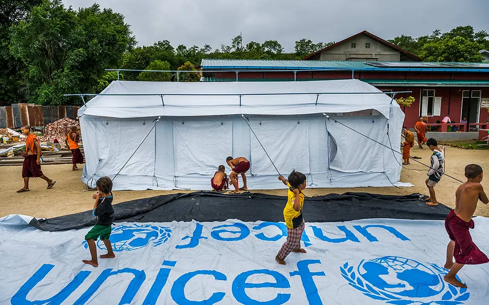 Myanmar Erdbeben spenden: Kinder packen spielerisch beim Aufbau eines großen UNICEF-Zeltes mit an. 