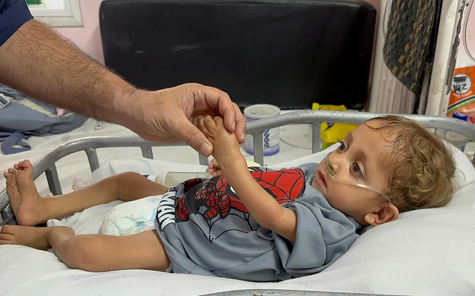 Ein Kleinkind wird im Krankenhaus beatmet und hält die Hand eines Mannes fest. | © UNICEF/Eleyan Gaza spenden: Ein Kleinkind wird im Krankenhaus beatmet und hält die Hand eines Mannes fest.
