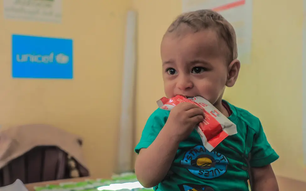 A small child eats therapeutic peanut paste against malnutrition
