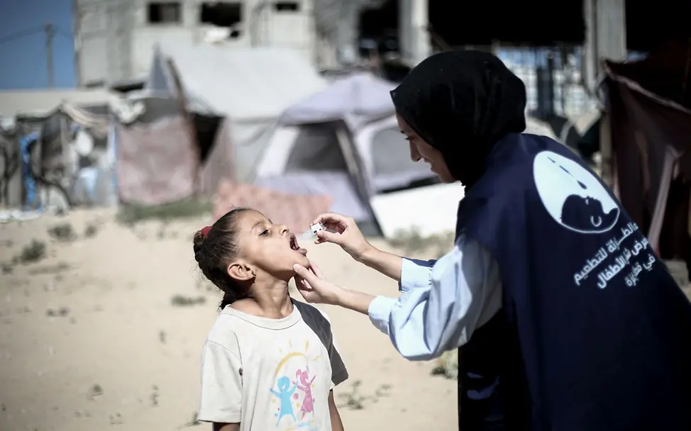 Eine Helferin in Gaza verabreicht einem Mädchen eine Schluckimpfung gegen Polio. I © UNICEF/El Baba UNICEF-Helfer*innen impften Hunderttausende Kinder in Gaza gegen Polio.
