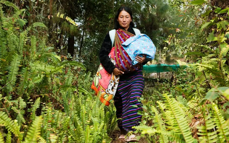 Eine junge Frau läuft mit ihrem Baby durch den Dschungel