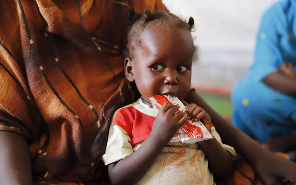 Fertige Nahrung in Form nährstoffreicher Erdnusspaste | UNICEF/Jamal Humanitäre Hilfe im Sudan: Ein Mädchen bekommt Erdnusspaste