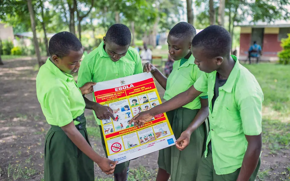 Ebola Aufklärung: Schülerinnen und Schüler in Uganda sehen sich gemeinsam ein Infoplakat zu Ebola an. 
