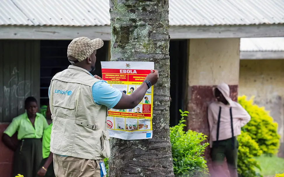 Ebola-Bekämpfung: Ein UNICEF-Helfer hängt in Uganda ein Ebola-Aufklärungsposter an einen Baum