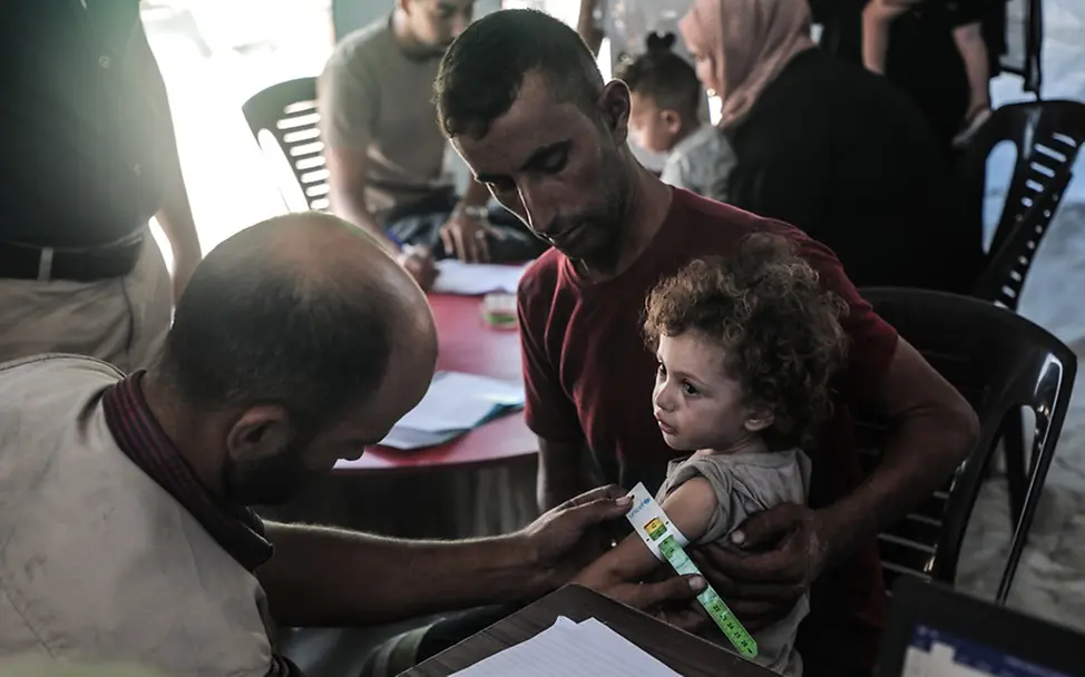 Im Gazastreifen sind Kinder an den Folgen von Mangelernährung gestorben | UNICEF/Nateel Gaza: Ein Gesundheitshelfer misst den Oberarm eines Kindes